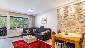 Una sala de estar moderna con un sofá modular, una mesa de comedor y una alfombra roja.