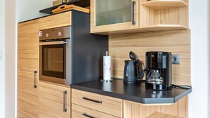 A modern kitchen with wooden cabinets, a built-in oven, a coffee maker, and a paper towel holder.