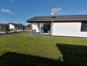 Un bâtiment moderne doté d’une antenne parabolique, d’un porche et d’une pelouse verdoyante.