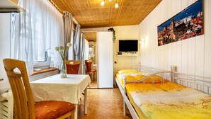 Une petite pièce agréable, avec un lit, une table, une chaise et un téléviseur.