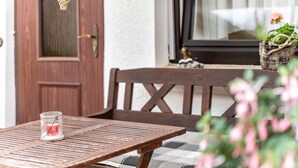Une table en bois avec une bougie, une chaise en bois et un coussin à carreaux.