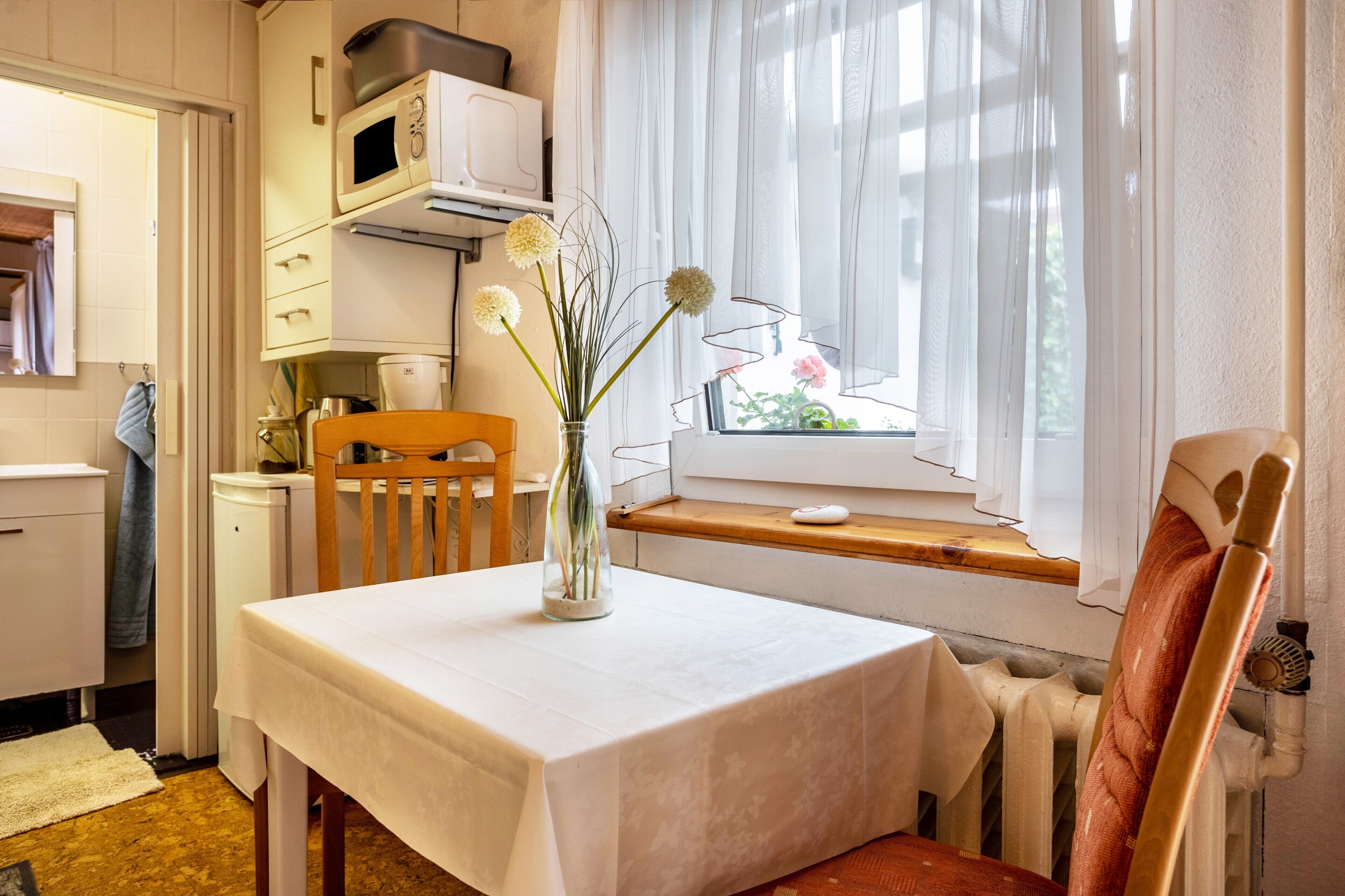 A kitchen with a table set for dining, a window with a view, and a radiator.