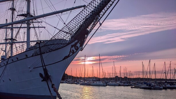 Un grand voilier était amarré dans une marina, et on pouvait apercevoir, au loin, plusieurs petits bateaux.