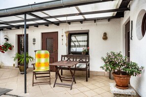 A patio with a table and chairs, a potted plant, and a hanging basket. - Studio Apartment 'Ferienzimmer Norbi Stralsund' with Private Terrace and Wi-Fi (Stralsund)