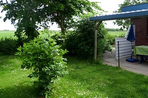 Zona patio con tavolo e sedie, circondata dal verde e affacciata sulla campagna.