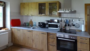 A kitchen with wooden cabinets, a microwave, an oven, and various utensils on the wall.