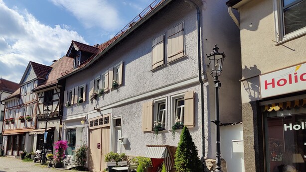A traditional European street with cobblestone pavement, historic buildings, and a shop with a sign reading 'Holo'.