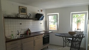 A kitchen with a dishwasher, stove, and a dining table with chairs.