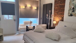 Een moderne slaapkamer met een groot bed, een klein rond tafeltje, een stoel en uitzicht door een raam.