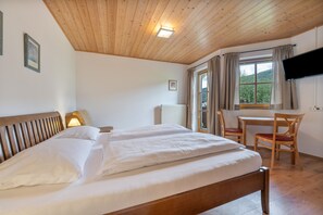 A room with a wooden ceiling, a bed with white linens, a desk with a chair, a television, and a window with curtains. - Apartment 'Appartment Roßbrand' with Mountain View, Shared Terrace and Wi-Fi (Radstadt)
