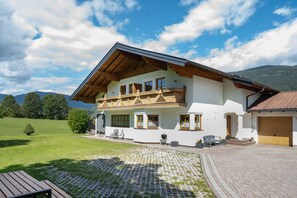 A two-story house with a balcony, a paved driveway, and a view of the mountains. - Apartment 'Appartment Roßbrand' with Mountain View, Shared Terrace and Wi-Fi (Radstadt)