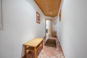 A hallway with a wooden table, a rug, and a door leading to another room.