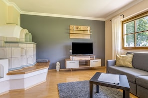 A living room with a flat-screen TV, a sofa, a coffee table, and a decorative vase.