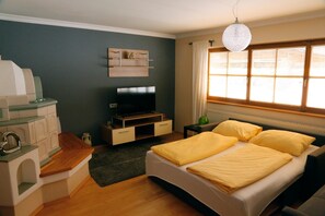 Ein Schlafzimmer mit einem Bett, einem Fernseher, einem Regal und einem Fenster mit Vorhängen.