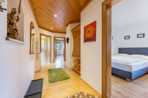A hotel room with a bed, a wooden floor, a green rug, a wooden ceiling, and a painting on the wall.