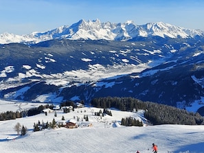 A snow-covered mountain landscape with a ski resort, including buildings and ski slopes.
