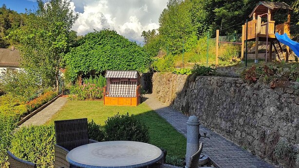 A patio with wicker furniture, a small shed, and a play structure.