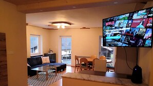 A living room with a sofa, coffee table, and TV displaying Netflix content.