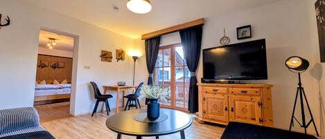 Una sala de estar moderna con una mesa redonda, un sofá, un televisor y un mueble de madera.