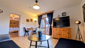 A modern living room with a round table, a sofa, a TV, and a wooden cabinet. - Apartment 'Arnspitze' with Mountain View, Balcony and Wi-Fi (Mittenwald)