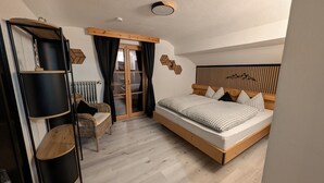 A bedroom with a bed, a chair, a shelf, and a radiator. - Apartment 'Wetterstein' with Mountain View, Balcony and Wi-Fi (Mittenwald)