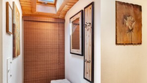 A narrow hallway with a wooden door, a bench, and artwork on the walls. - Apartment 'Wetterstein' with Mountain View, Balcony and Wi-Fi (Mittenwald)