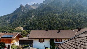 A mountain village with traditional houses, a clear sky, and a prominent mountain range in the background. - Apartment 'Wetterstein' with Mountain View, Balcony and Wi-Fi (Mittenwald)