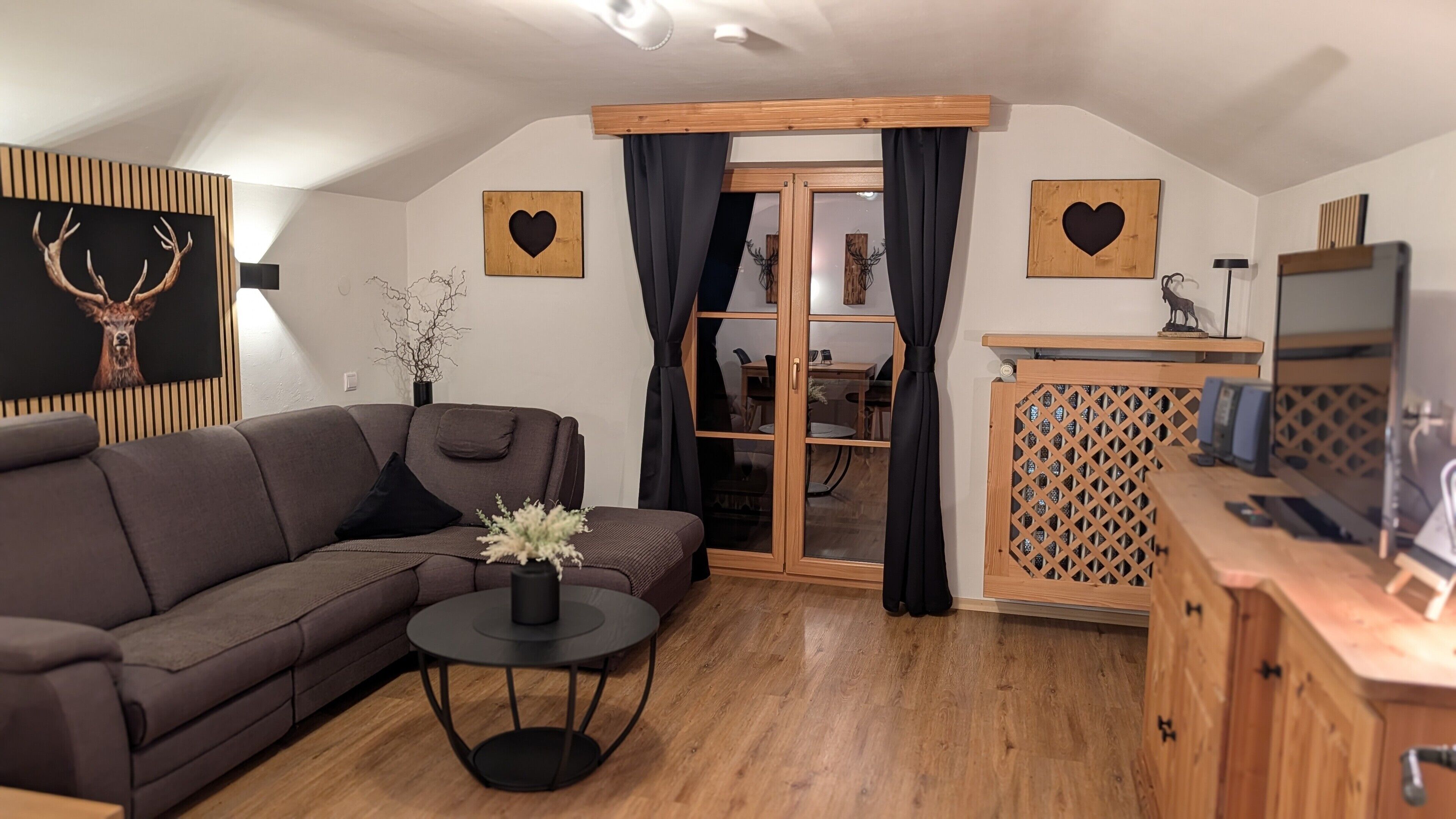 A living room with a sofa, a small round table, a cabinet, and a glass door leading to a dining area.