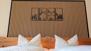A bed with a wooden headboard, two pillows, and a wall with vertical wooden slats and a black silhouette artwork. - Apartment 'Wohnung 1' with Mountain View, Balcony and Wi-Fi (Mittenwald)
