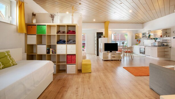 A modern living room with a sofa, TV, and a dining area with chairs.