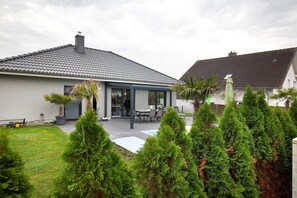 A residential house with a covered patio, a lawn, and a swimming pool. - Apartment 'Großzügige Wohnung' with Shared Pool, Private Terrace and Wi-Fi (Brechen)