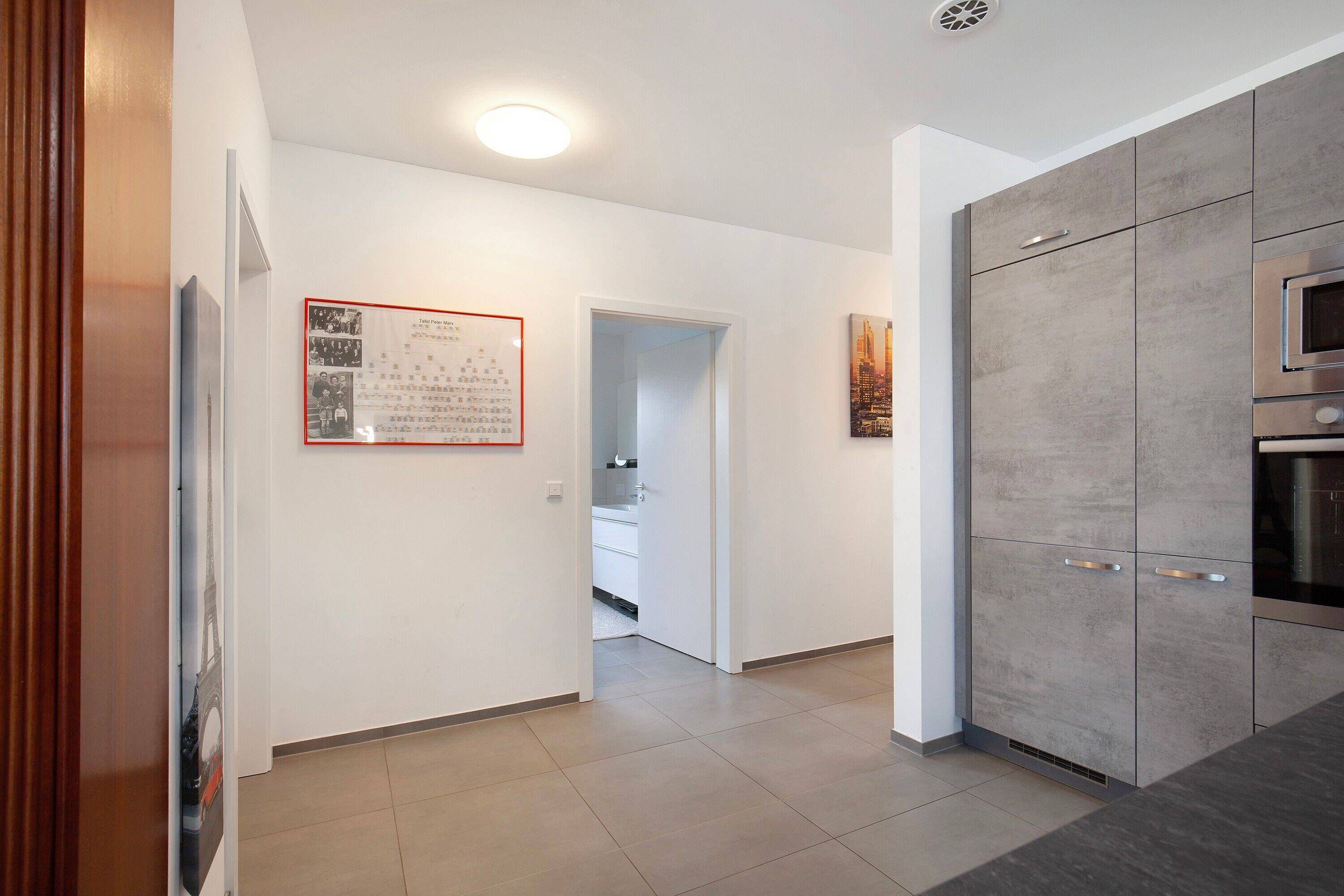 A modern kitchen with grey cabinets, a stainless steel oven, and a tiled floor.