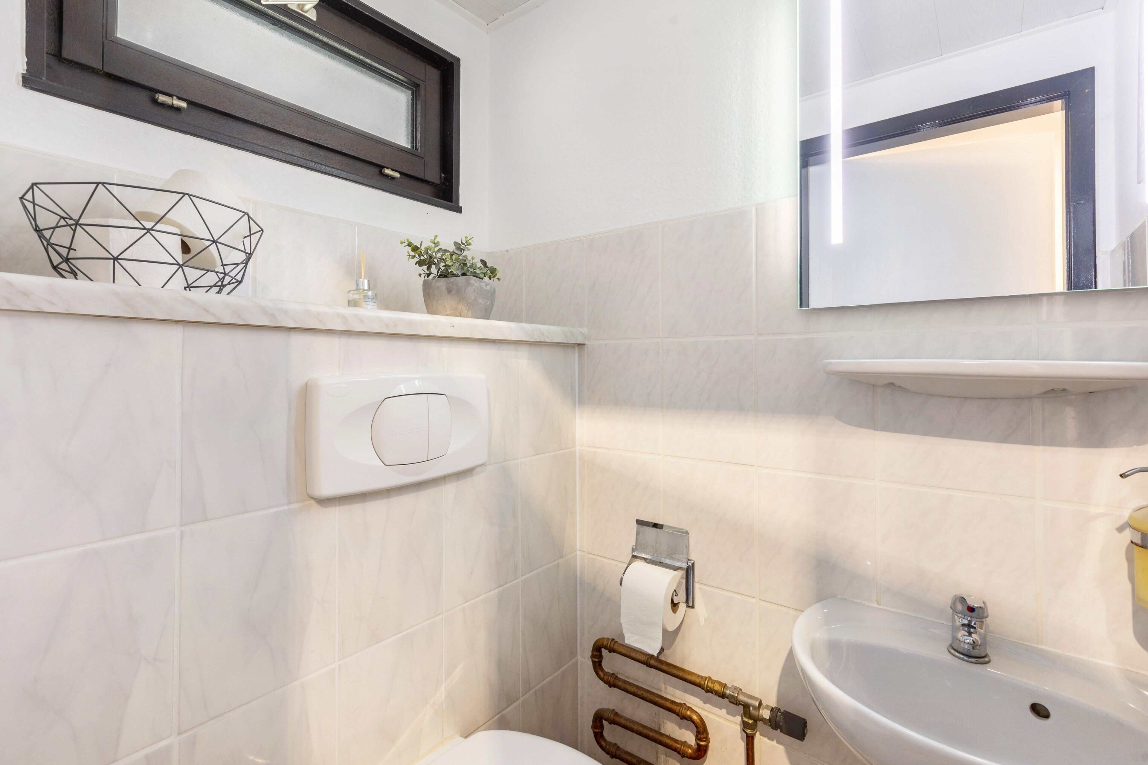 A bathroom with a toilet, sink, towel rack, and a mirror.