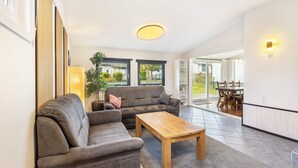 Een moderne woonkamer met twee banken, een houten salontafel en een eethoek met een tafel en stoelen.