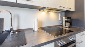 Een moderne keuken met een roestvrijstalen afzuigkap, een ingebouwde koffiemachine en een strak aanrecht.