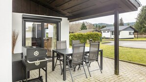Eine Terrassenanlage im Freien mit Grill, Esstisch und Stühlen.