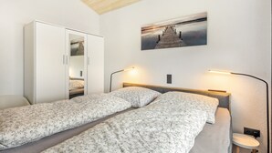 Ein Schlafzimmer mit zwei Einzelbetten, einem Kleiderschrank, einem Nachttisch, einer Lampe und einem Bild an der Wand.