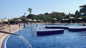A large swimming pool with a clear blue water feature, surrounded by lounge chairs and umbrellas.