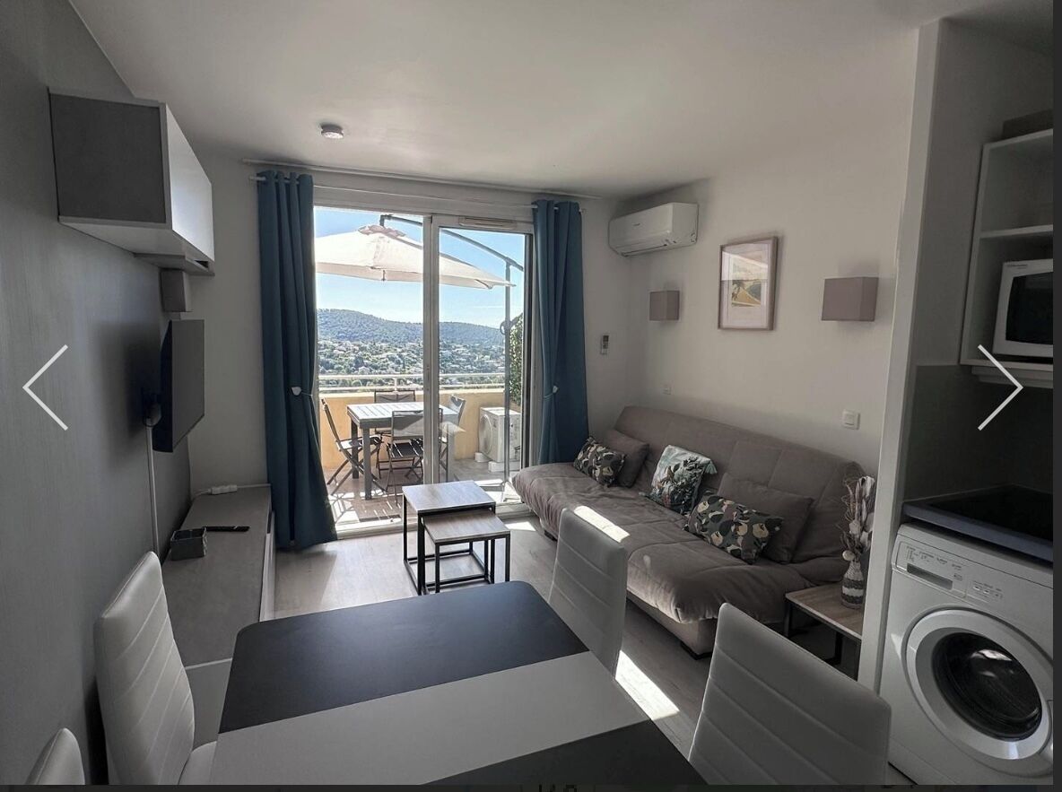 A modern living room with a sofa, a small table, a washing machine, and a TV.