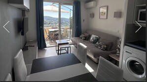 Una sala de estar moderna con un sofá, una mesita, una lavadora y un televisor.