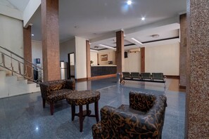 A lobby with a reception desk, seating area, and a staircase. - Nusa Indah Syariah Bandara By Abdihome (Tangerang)