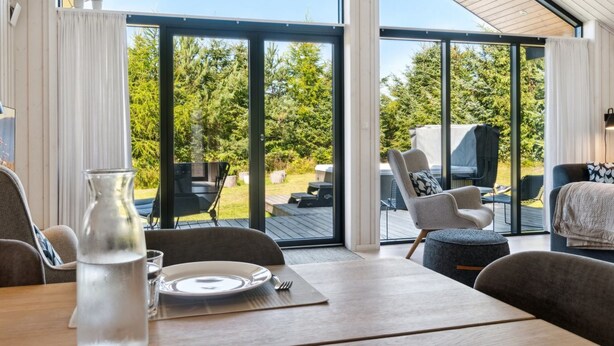 A dining area with a table set for two, large windows, and a view of the outdoors. - "Kristiarn" - 1.1km from the sea by Interhome (Aakirkeby)