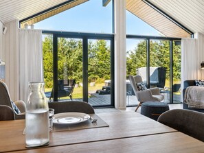 A dining area with a table set for two, large windows, and a view of the outdoors. - "Kristiarn" - 1.1km from the sea by Interhome (Aakirkeby)