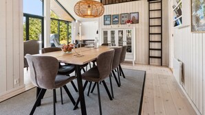 A dining area with a wooden table, grey upholstered chairs, a woven pendant light, and a view of the outdoors. - "Kristiarn" - 1.1km from the sea by Interhome (Aakirkeby)