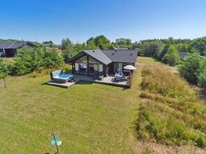 Une maison moderne dotée d’un patio, d’un espace salon extérieur et d’un jacuzzi.