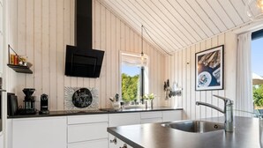 A modern kitchen with white cabinetry, a black countertop, a stainless steel sink, and a black range hood. - "Kristiarn" - 1.1km from the sea by Interhome (Aakirkeby)