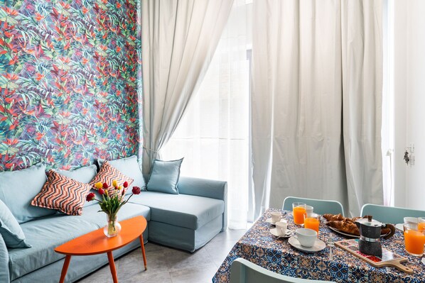 Sala de estar moderna com sofá, mesa de centro e um serviço de café da manhã com croissants e suco de laranja.