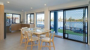 A modern kitchen with a dining area, large windows, and a view of a marina.