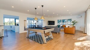 A spacious living area with a pool table, a sofa, and a TV.