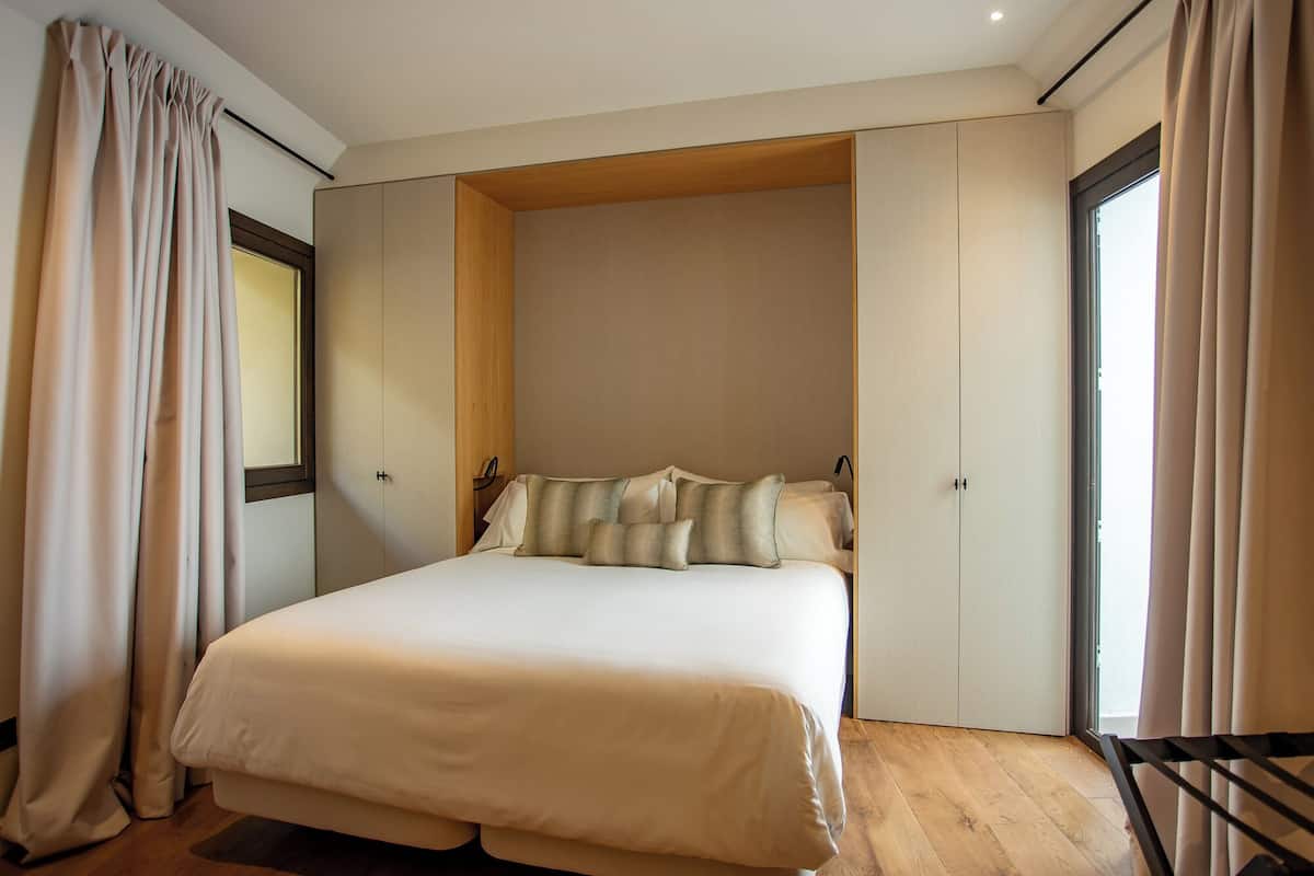 Un dormitorio moderno con una cama grande, paneles de madera y vistas por una ventana.